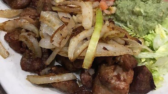 Carne Asada · Slices of ribeye steak grilled with onions. Served with rice, beans guacamole salad and tortillas.