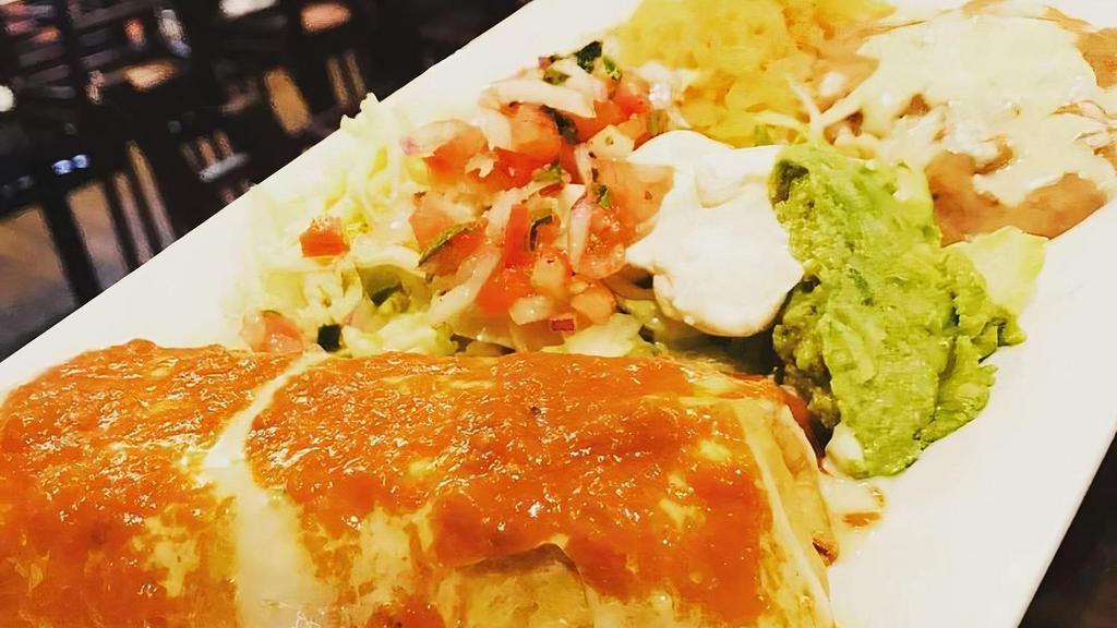 Super Chimichanga · Two flour tortillas deep fried, one chicken, one beef. Topped with cheese dip and garnished with guacamole salad and beans.
