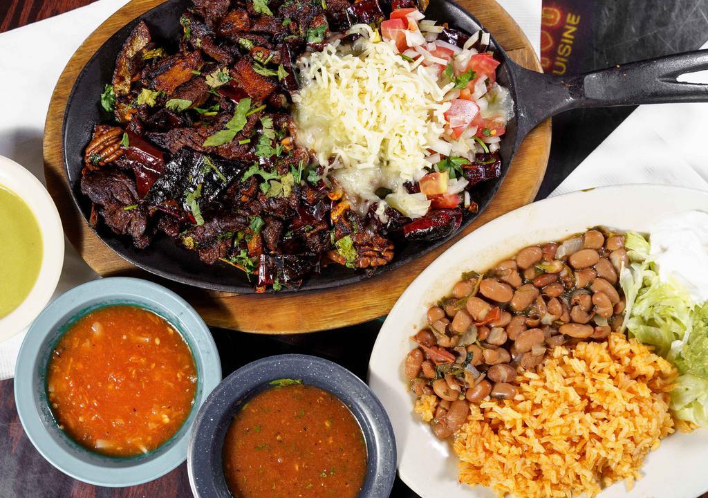 Fajita Al Guajillo · Tender, sizzling chicken, beef or pastor, sautéed with sun dried peppers, pecans, raisins, peanuts, grilled onions and poblano. Served with guacamole, sour cream, rice, charro beans, corn or flour tortillas.