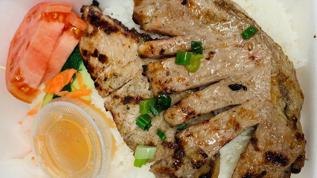 Com Suon Nuong · Grilled pork chop, cucumber and tomatoes.