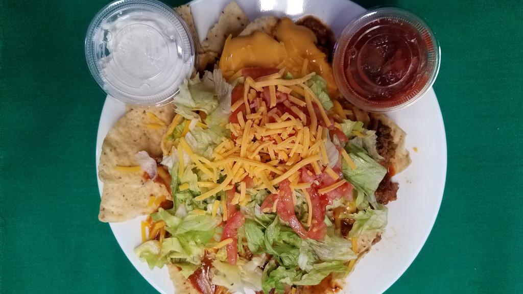 Taco Salad · Tortilla Chips topped with Seasoned Ground Beef, Chili, Nacho Cheese, Lettuce, Diced Tomato & Cheddar Cheese. Served w/ sour cream & salsa on the side.