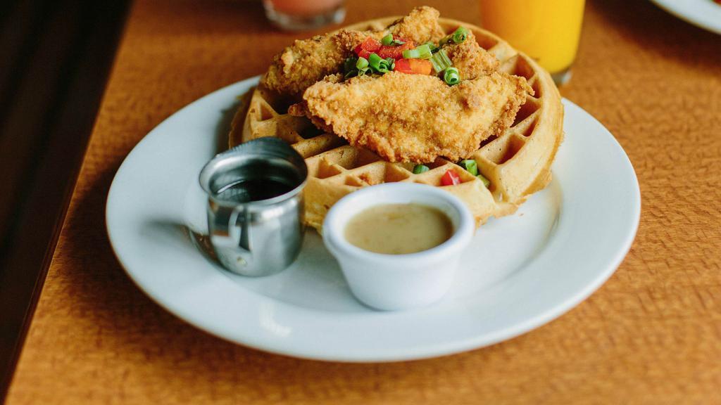 Chicken & Waffles · Our take on this classic.  Pan fried chicken strips piled high on a homemade Belgian waffle, smothered in our maple gravy and topped with finely chopped red peppers and green onions.