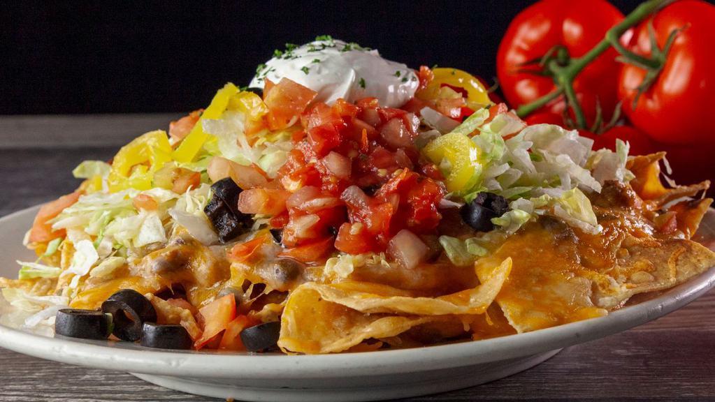 Ultimate Nachos · Crispy tortilla chips with melted cheddar and Monterey jack cheese, topped with our homemade chili. Dressed with fresh lettuce, diced red tomatoes, banana pepper rings, and sliced black olives. Served with salsa and sour cream.