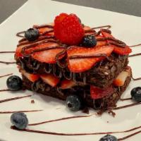 Brownie & Berries · Two brownies topped with berries and chocolate sauce.