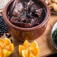 Feijoada · Black Beans Stew cooked with Bacon, Pork meats, Sausages served with rice, collard greens, y...