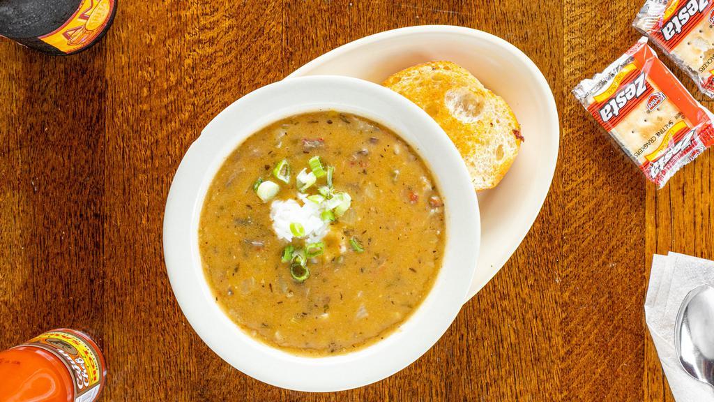 Crawfish Etouffeé (Small) · A thick crawfish stew, made with celery, bell peppers, onions, mushrooms, served with a scoop of rice on top, two slices of toast on the side, and topped with green onions.