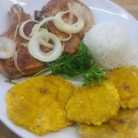 Chuleta De Puerco · Marinated pork chops grilled, garnished with sautéed onions.