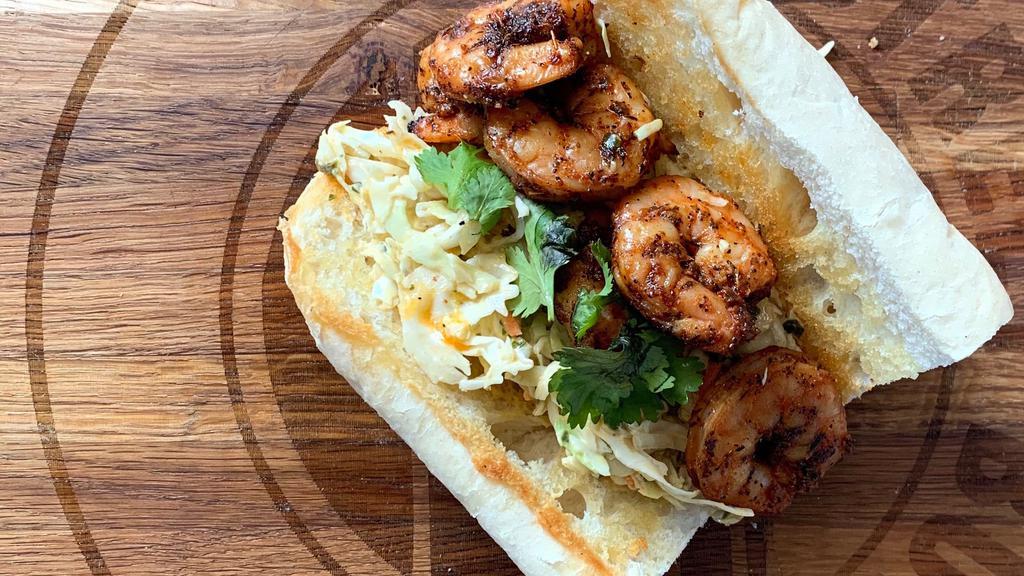 Blackened Shrimp Po'Boy · 6 medium blackened shrimp served on butter toasted New Orleans Gambinos French Bread atop a bed of Sriracha Slaw and topped with Cilantro.