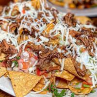 Birria Nachos · Crispy corn tortilla chips topped with beef birria, shredded cheese, beans, guacamole, sour ...