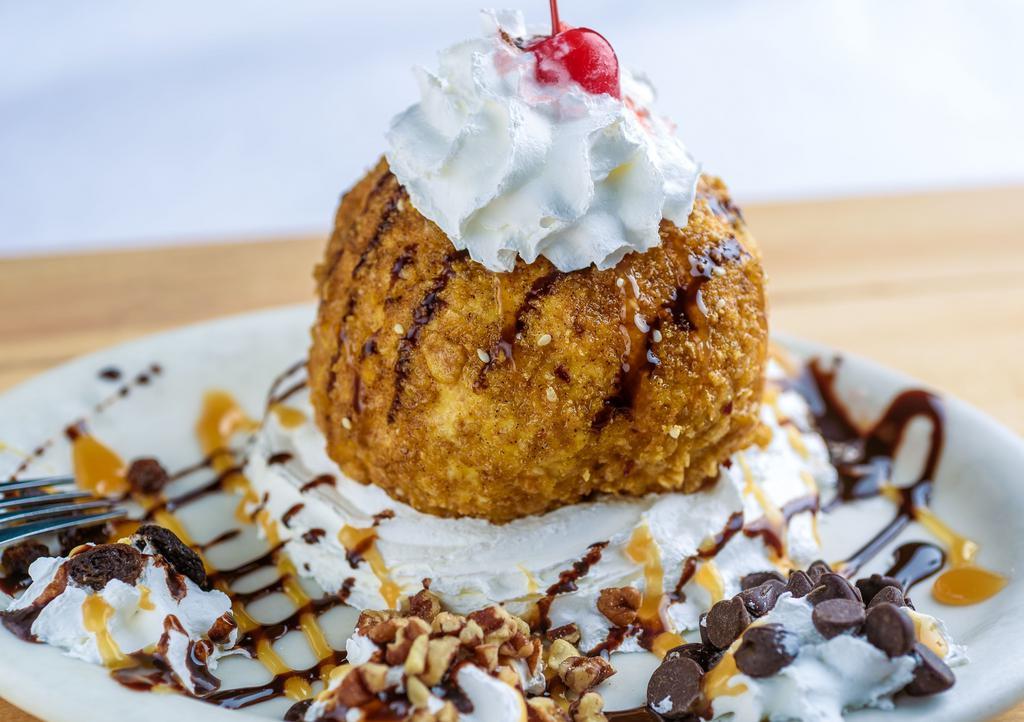 Huckleberry Fried Ice Cream · Made with fresh huckleberry and vanilla ice cream, lightly battered with corn flakes, chili flakes, and sesame seeds then topped with pecans, huckleberry sauce, and whipped cream.