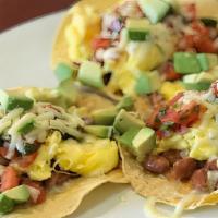 Huevos Rancheros · Three(3) tostada shells topped with pinto beans, diced avocado and scrambled eggs with a spr...
