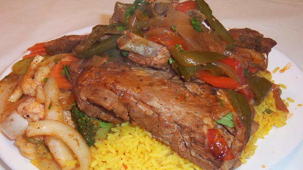 Costillas De Puerco · Braised Peruvian pork ribs with vegetables and seasoned rice.