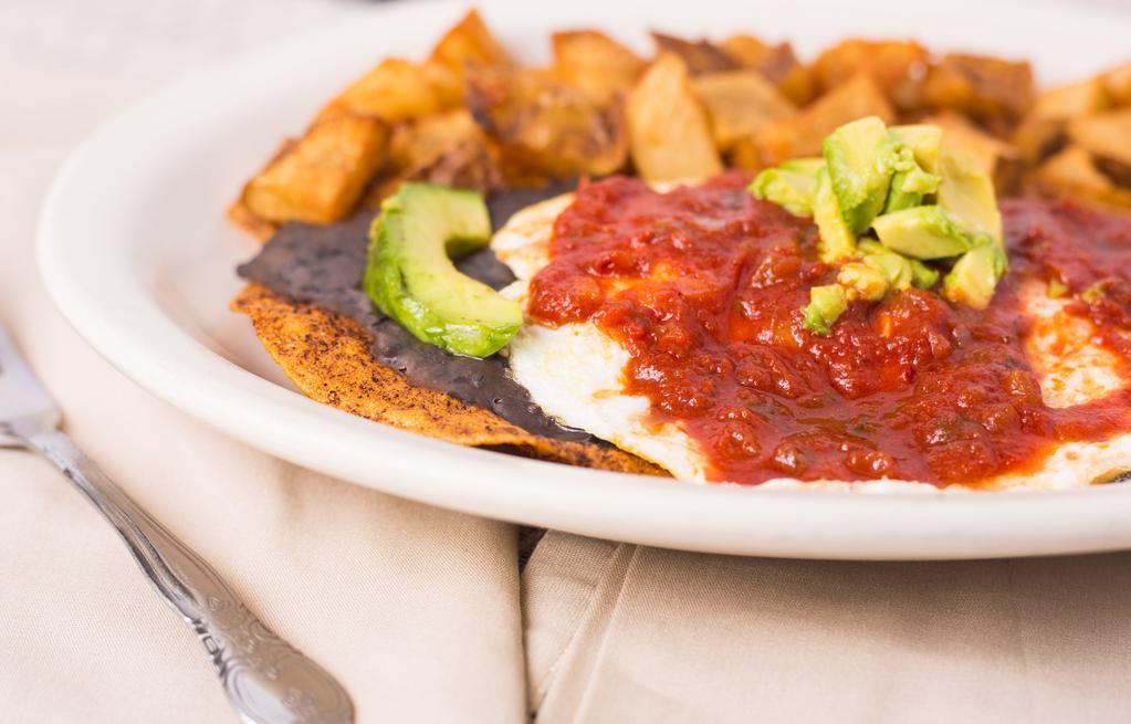 Huevos Rancheros · Two crispy tortillas topped with black beans, avocado, eggs over easy and ranchera sauce, served with country potatoes.