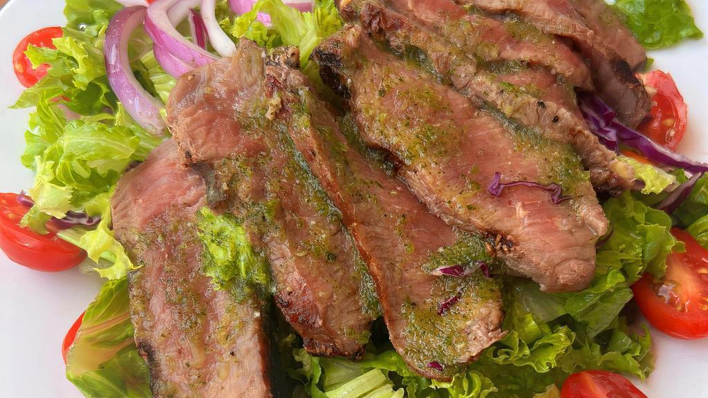Soi Steak Salad · A summer salad, topped with grilled ribeye steak, and served with a side of sour & spicy cilantro dressing.