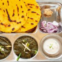 Saag & Makki Ki Roti · Mustard leaves and spinach curry served with two pieces of cornbread.