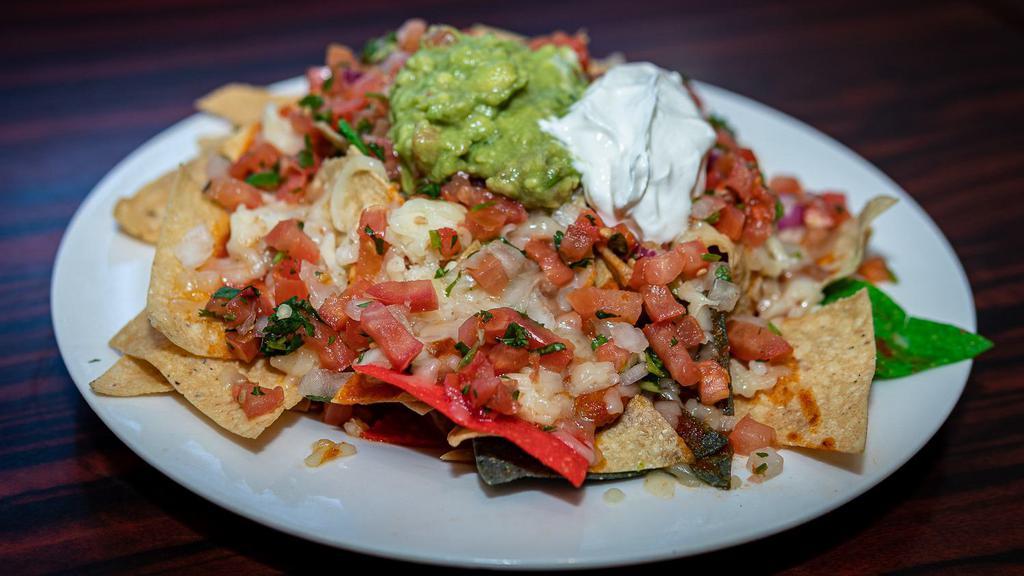 Super Nachos · Lettuce, tomato, cheese, olives, jalapeños, meat, and beans.