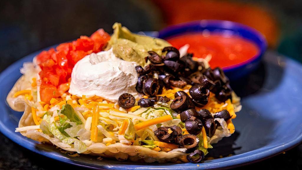 Wild Tostada Salad · Salad shell, shredded beef, lettuce, cheese, guac, sour cream, tomato, and olives.