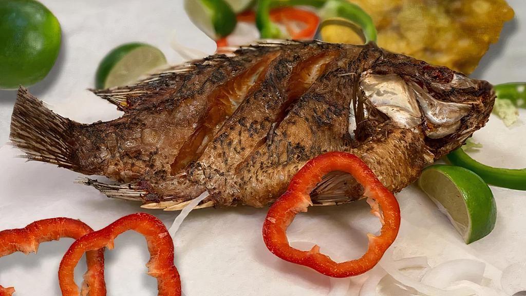 Pescado Frito · Fresh fried whole tilapia topped with sauteed bell peppers & onions; served with white rice, salad, & green plantains