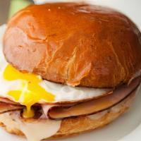 Egg, Ham & Cheese Breakfast Sandwich · Two scrambled eggs with cheddar cheese and three slices of Canadian bacon on a buttered brio...