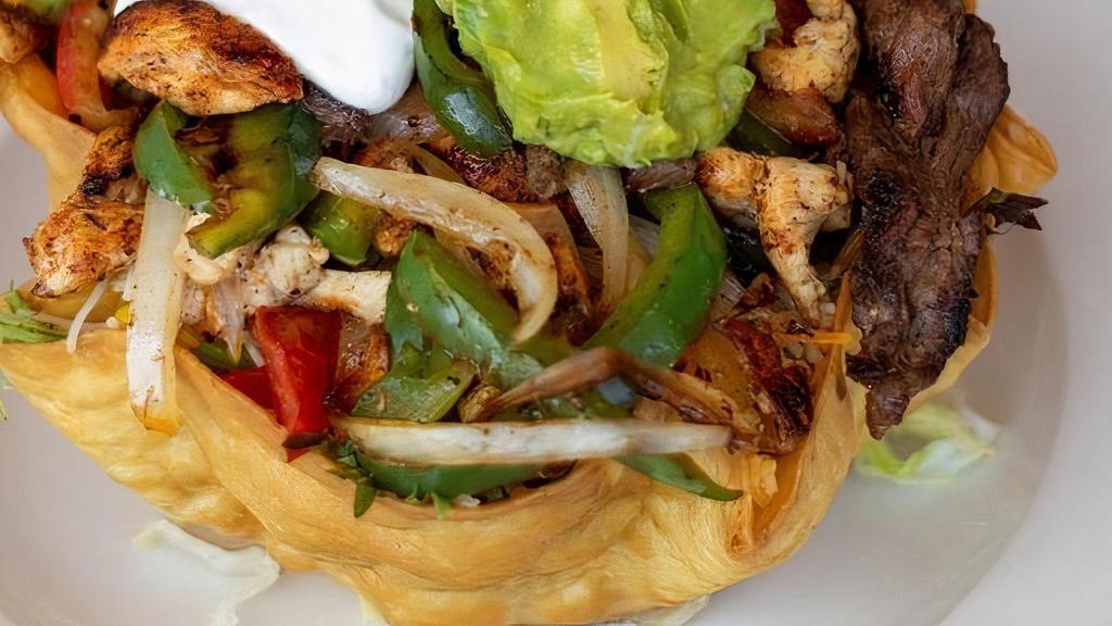 Taco Salad Cancun · Flour tortilla bowl, stuffed with greens, roasted corn, guacamole, mango, sour cream, pico de gallo and Mexican cheese, topped with grilled chicken, grilled steak, onions and green peppers.