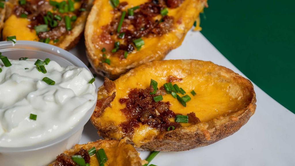 Potato Skins · Fried potato shells filled with melted Cheddar, bacon and chives. Served with sour cream.