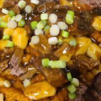 Poutine · A large plate of fries topped with fresh cheese curds, brisket, brown gravy, and green onion...