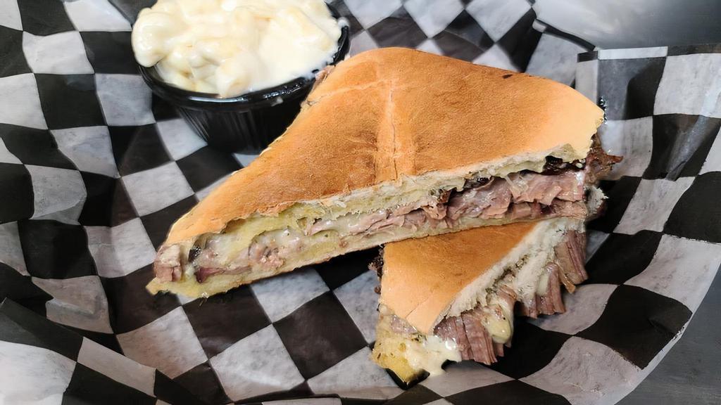 Brisket Garlic Melt · Our smoked brisket with provolone cheese, green chili aioli, and onions lightly pressed on cuban bread with our special garlic butter.  Served with your choice of one side