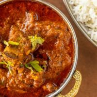 Goat Curry · Bone in goat cooked together with south Indian spices, and spicy curry. Served with a side o...