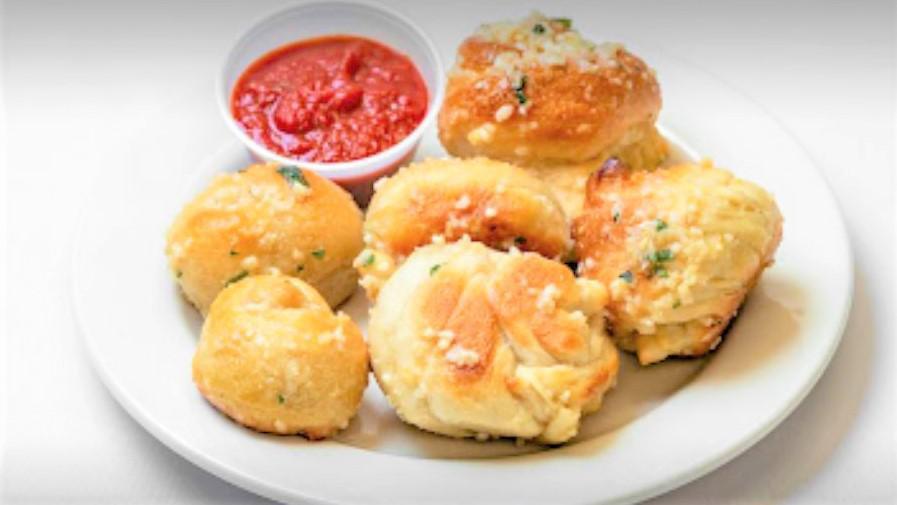 Garlic Knots · A classic snack, our garlic knots are strips of pizza dough tied in a knot, baked, and then topped with melted butter, garlic, and parsley.