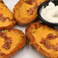 Potato Skins · Homemade extra large, double-cooked skins topped with melted cheese and bacon, served with s...