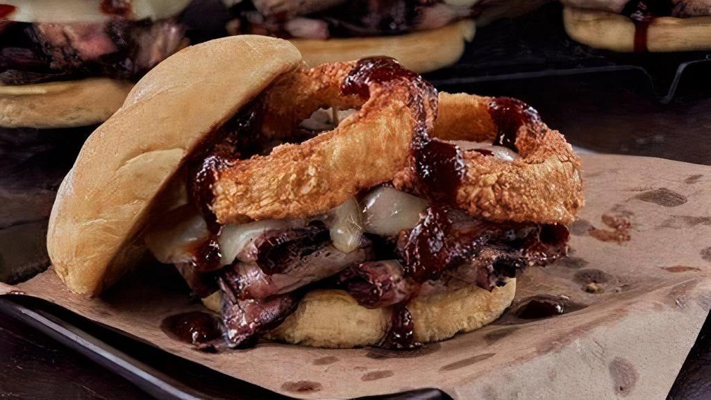 The Z-Man · Slow-smoked beef brisket, smoked provolone cheese, topped with onion rings, on a toasted Kaiser bun