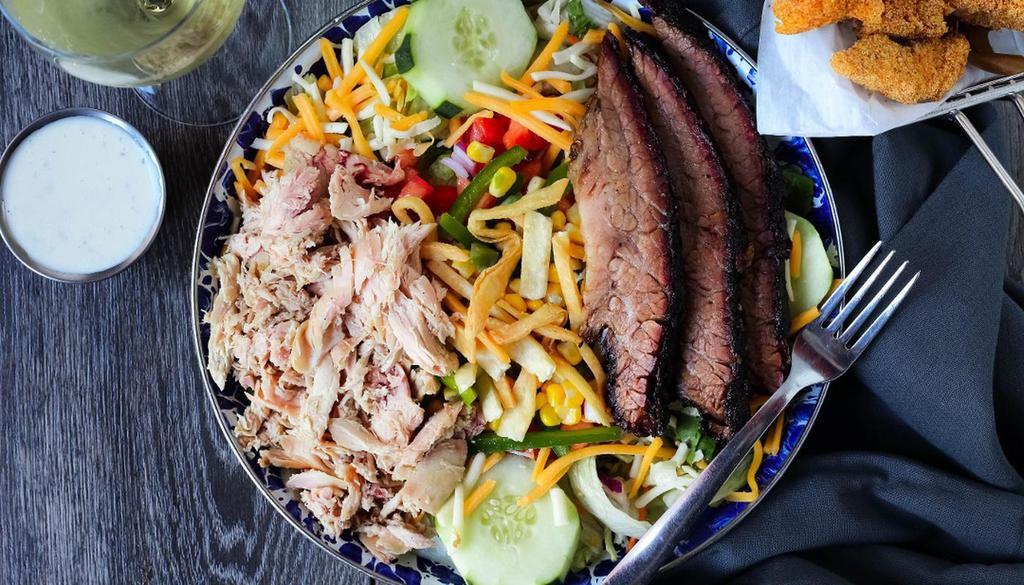 Smokehouse Salad. · Pulled chicken and Texas brisket over greens with roasted corn mix, fresh cut cucumbers, red onions, tomatoes, topped with cheddar & jack cheese, and tortilla strips.