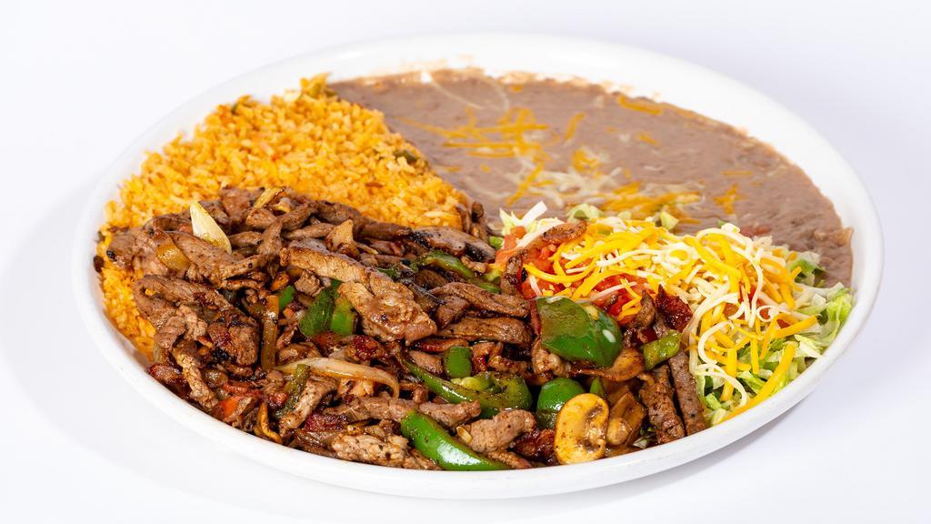 Steak Sorpresa · Steak strips sautéed with bell peppers, onions, tomatoes mushrooms, and bacon garnished with lettuce, tomatoes and cheese. Served with rice beans and tortillas.