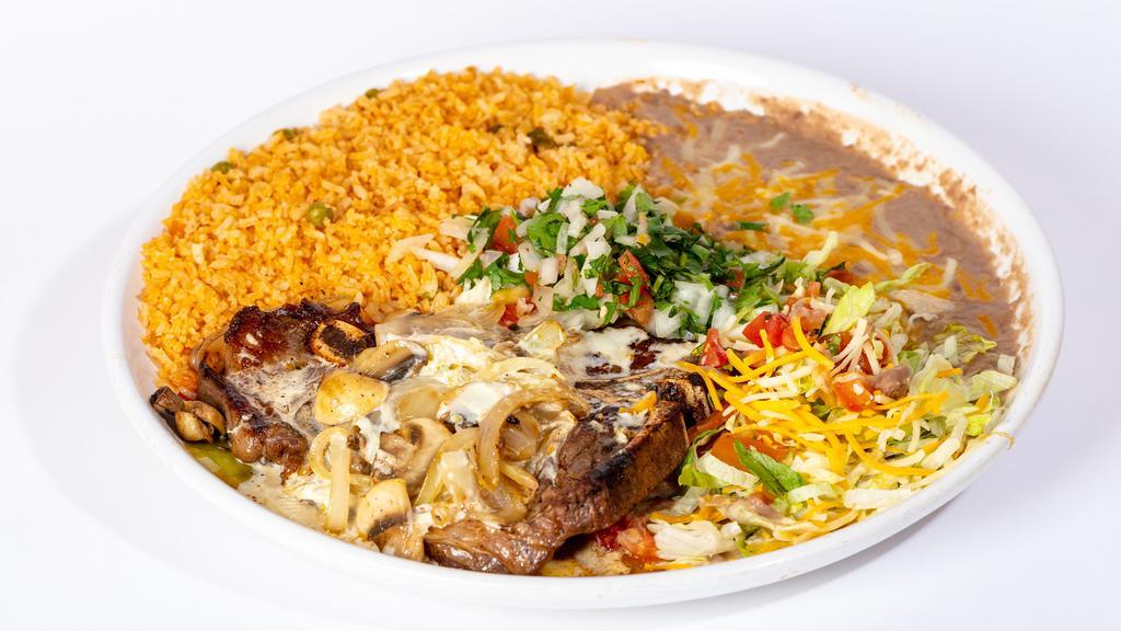 Steak Del Valle · T-bone steak grilled with onions and mushrooms. Smothered in our special white queso dip. Garnished with lettuce, cheese and pico de gallo. Served with rice, beans and tortillas.