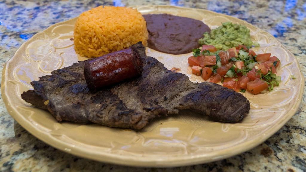 Churrasco A La Plancha · Skirt steak served with rice, beans, chorizo, guacamole, and pico de gallo.