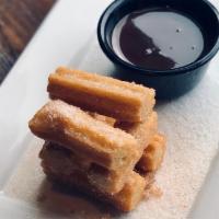 Churros. · Fried churros tossed with cinnamon sugar and served with a side of hazelnut-chocolate dippin...