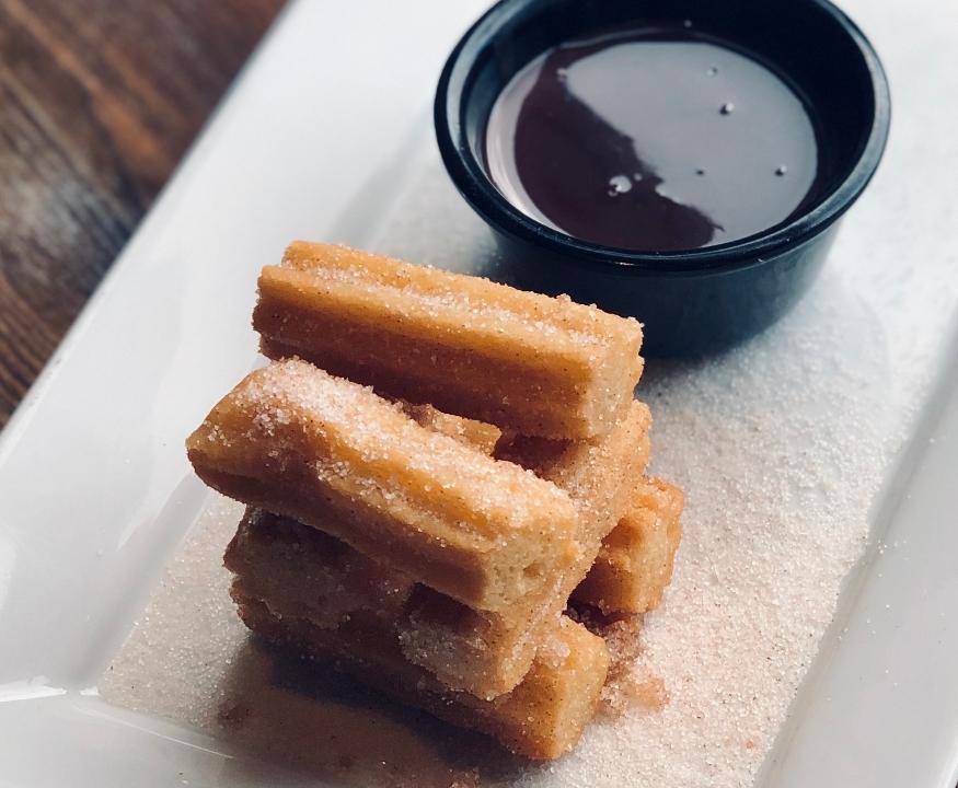 Churros. · Fried churros tossed with cinnamon sugar and served with a side of hazelnut-chocolate dipping sauce