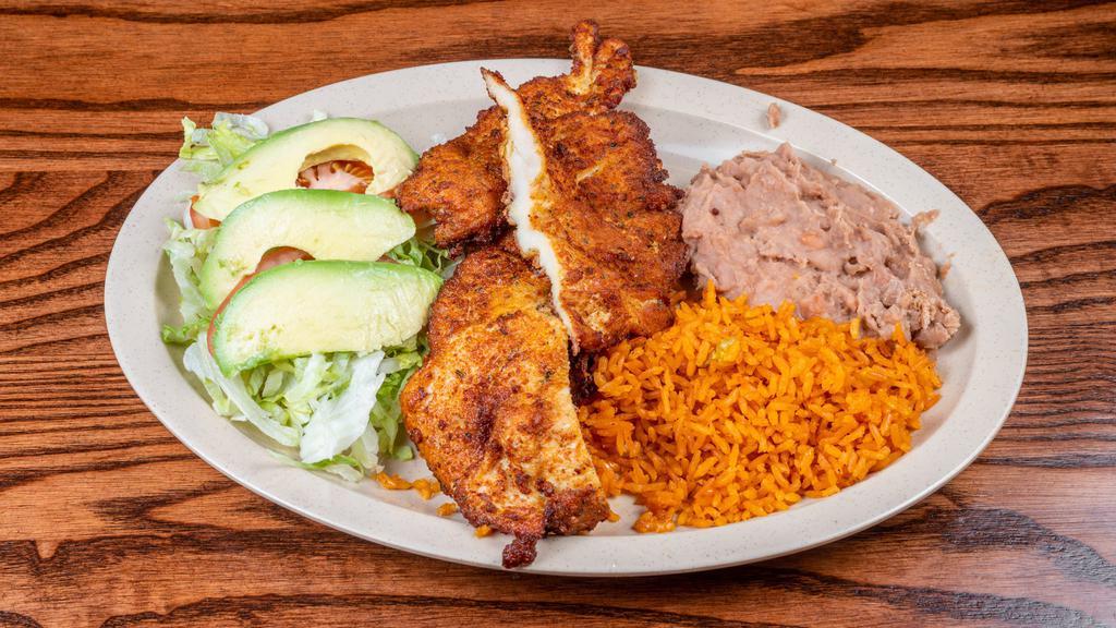 Milanesa / Milanese · Carne empanizada servida con aguacate, arroz y frijol. / A breaded steak served with rice, beans, and salad.
