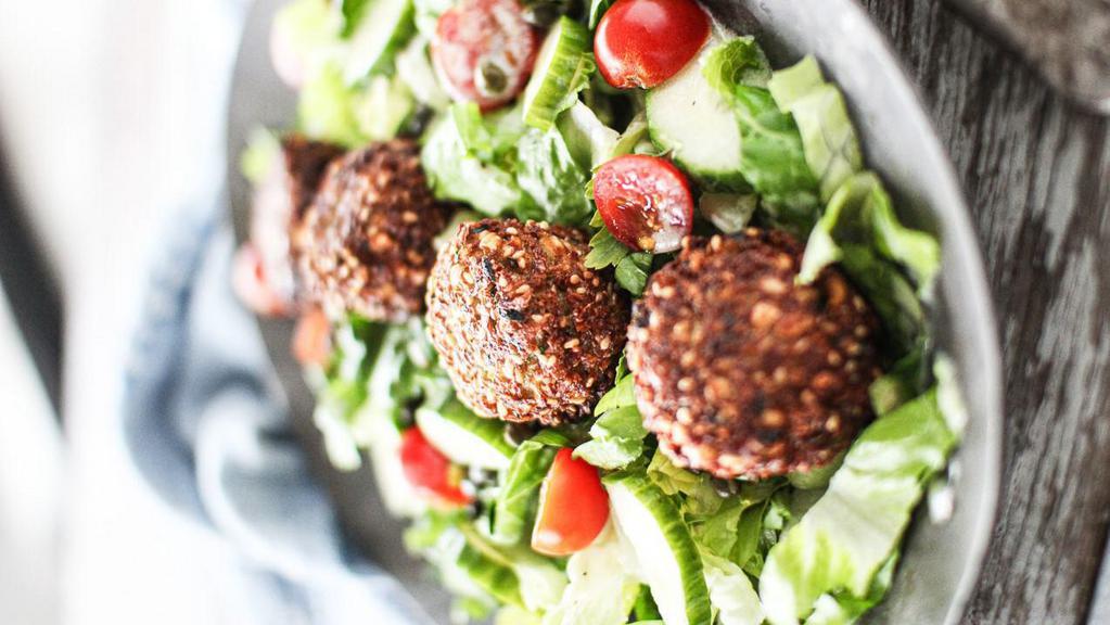 Falafel Salad · Gluten-free. Vegetarian. Chickpeas, fava beans, onions, garlic, parsley, and cilantro fried in a bull-shaped patty, on a salad of mixed greens, cucumbers, tomatoes, Feta, olives, signature white sauce, and hot sauce.