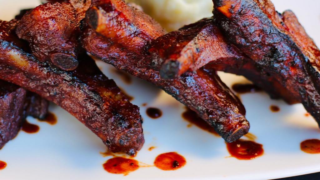 Baby Back Ribs · Finished over an open fire grill with our tangy & spicy signature pomegranate BBQ sauce. (Gluten Free)