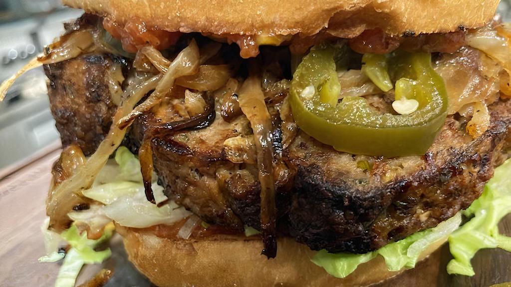 Couch Potato Burger · Pan seared slab of green chili meatloaf, grilled onions, mama Tuddy's candied jalapeños, bloody Mary ketchup. All burgers served on a brioche bun with shredded lettuce, fresh tomato, and mama Tuddy's bread and butter pickles.