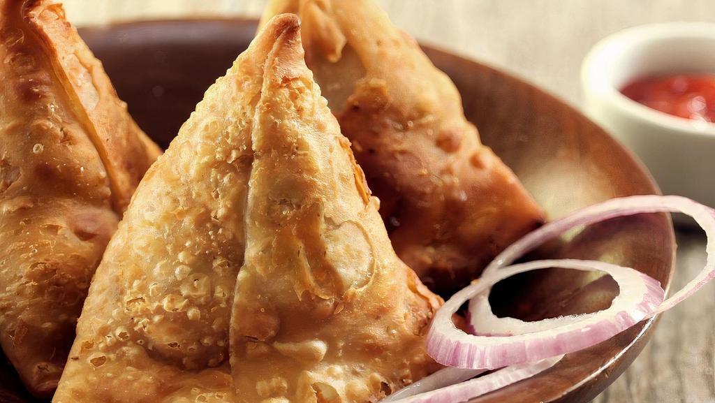 Samosa (3 Pieces) · Deep-fried pastry filled with mashed potatoes, green peas, spices & herbs served with a spicy cilantro-mint & a sweet tamarind chutney (Vegetarian, Vegan, Nut-Free)