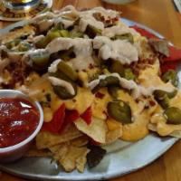 Loaded Smoked Chicken Nachos · A bed of nacho chips, topped with applewood smoked chicken, local made queso, bacon, 'que so...