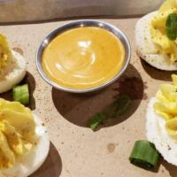 Deviled Eggs · Four deviled eggs topped with candied bacon and served with a side of paprika aioli dipping ...