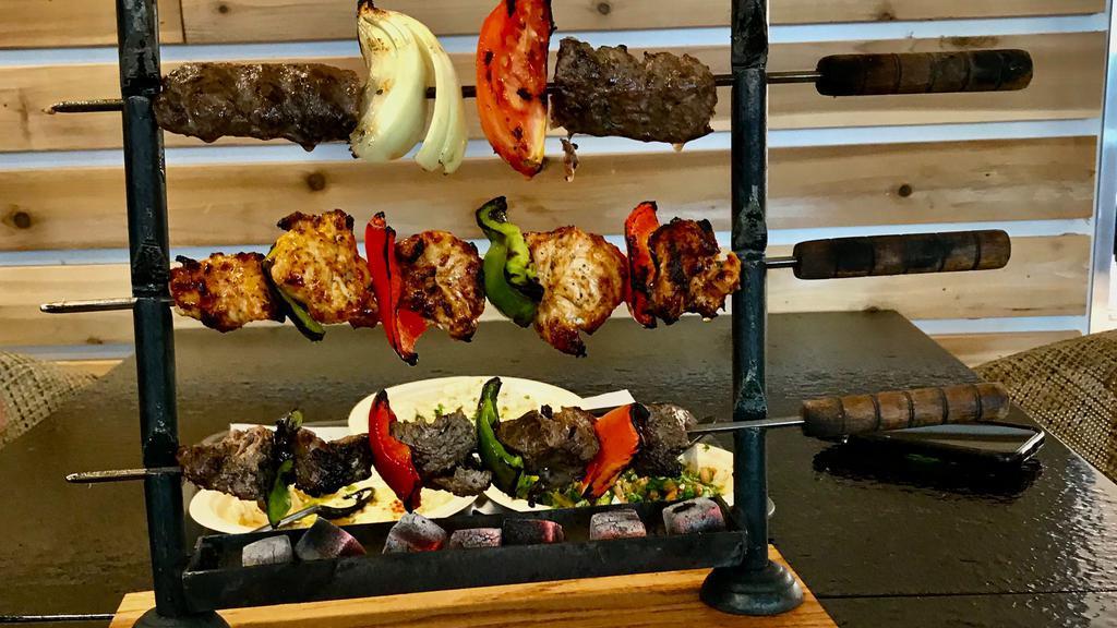 Phoenician Mixed  Grill For ((2)) · A combination of beef tenderloin, chicken shish tawook, lamb kabob, grilled red peppers, green peppers, onions & tomatoes ((on a mini BBQ grill for dine-in only)) Served with 4 sides of your choice.