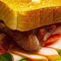 Turkey Club Sandwich · Sliced smoked turkey with garlic aioli, lettuce, tomato, cheddar cheese, and crispy bacon on...