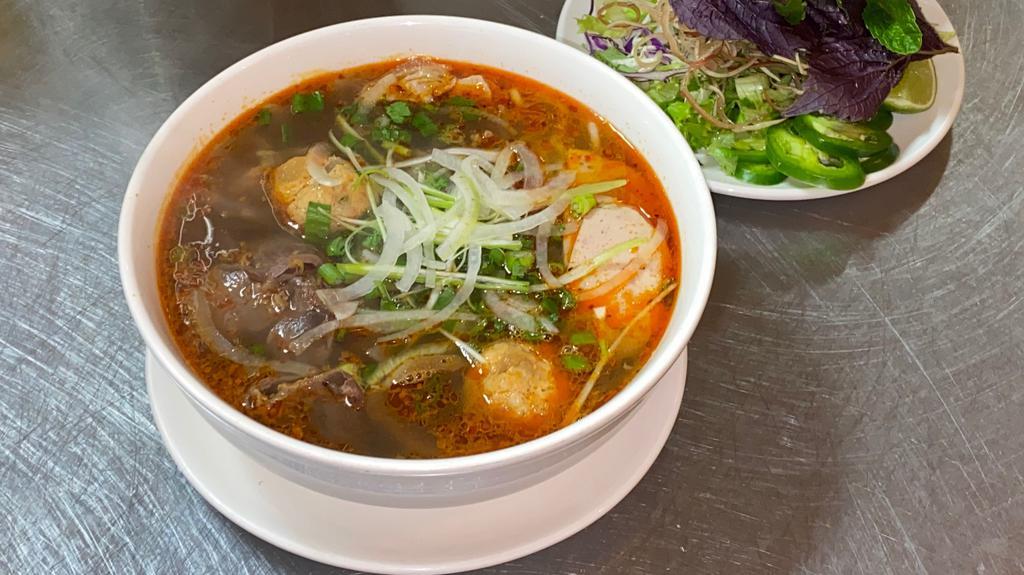 Bún Bò Huế / Spicy Beef Noodle Soup · Served spicy. Round Shanghai rice noodle, beef shank, slice Vietnamese pork ham, & pork picnic in a spicy lemongrass beef broth.