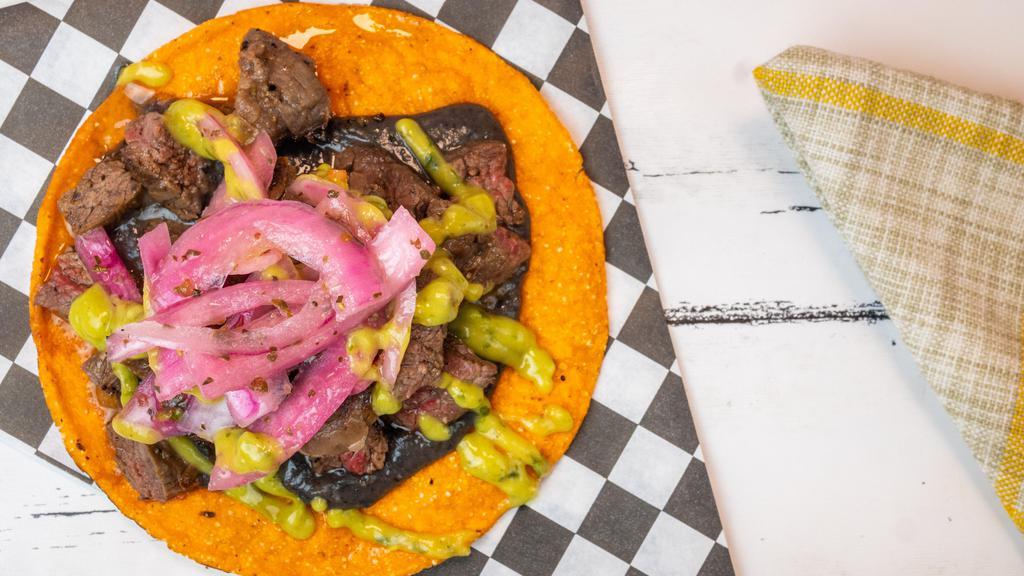 Tostadas · Two tostadas topped with black beans, meat of choice, pickled red onions, drizzled with creamy avocado sauce.