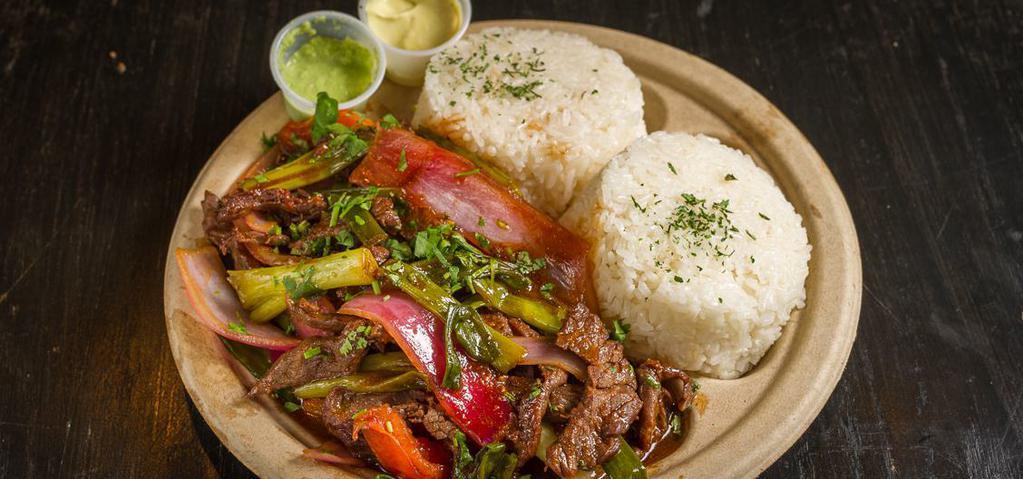 Lomo Saltado · Peruvian stir fry combing marinated beef, red onions, spring onions, tomatoes and cilantro served over a bed of fries and rice.