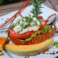 Avocado Toast · A whole avocado spread over our griddled milk bread topped with sliced tomatoes, goat cheese...